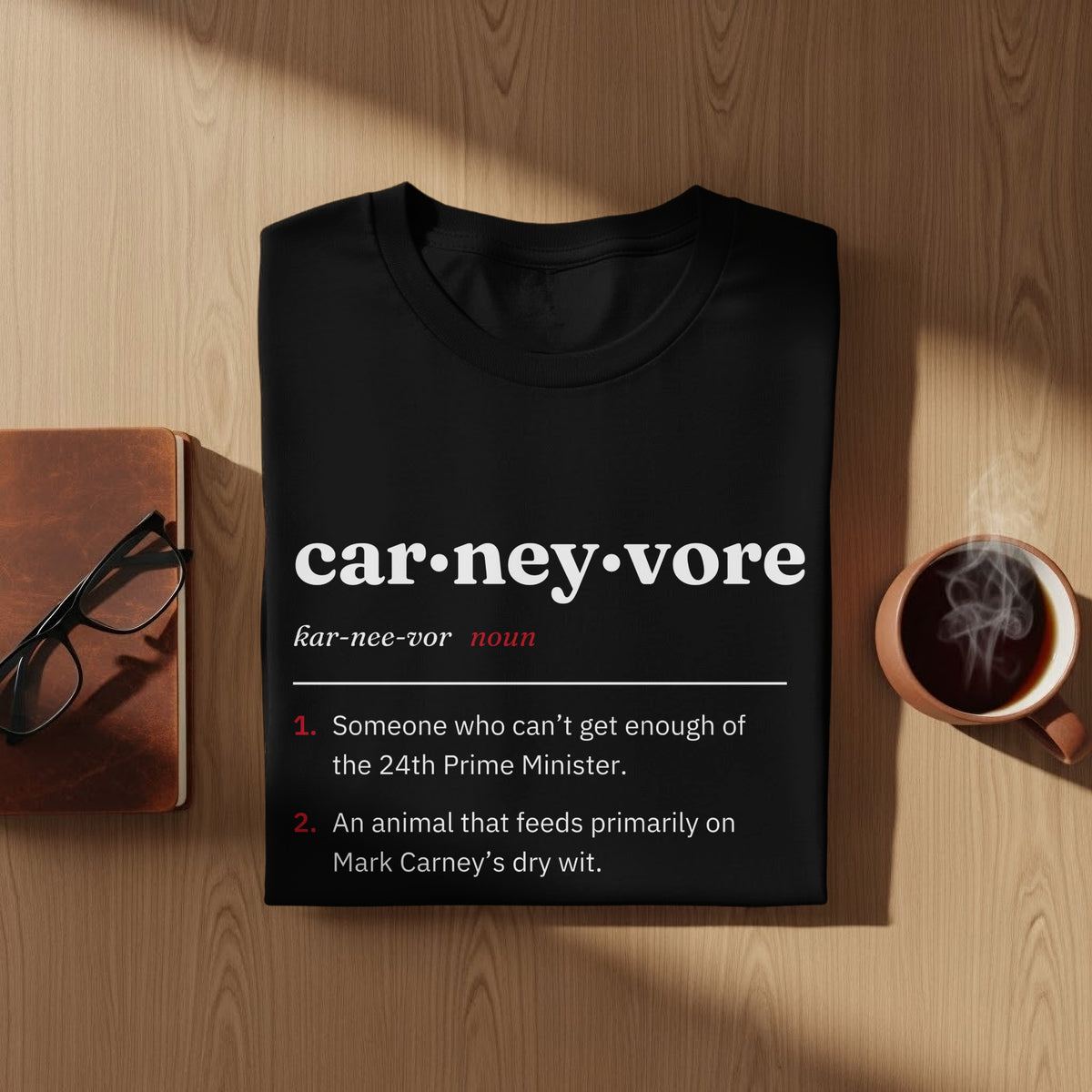 Black t-shirt with "car-ney-vore" definition, a joke about Mark Carney.