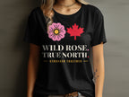 Black t-shirt with a pink wild rose, red maple leaf, and text.