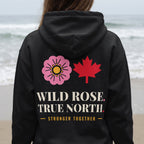 Black hoodie with pink wild rose, red maple leaf, and text "WILD ROSE. TRUE NORTH. STRONGER TOGETHER."