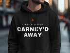 Black hoodie with white text "I GOT A LITTLE CARNEY'D AWAY" and a red maple leaf.