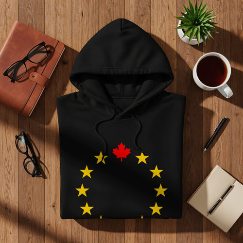 Black hoodie with yellow stars and a red maple leaf on a wooden background.