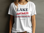 White t-shirt with text "LAKE ONTARIO" and "AMERICA" struck through, "CORRECTED" below.