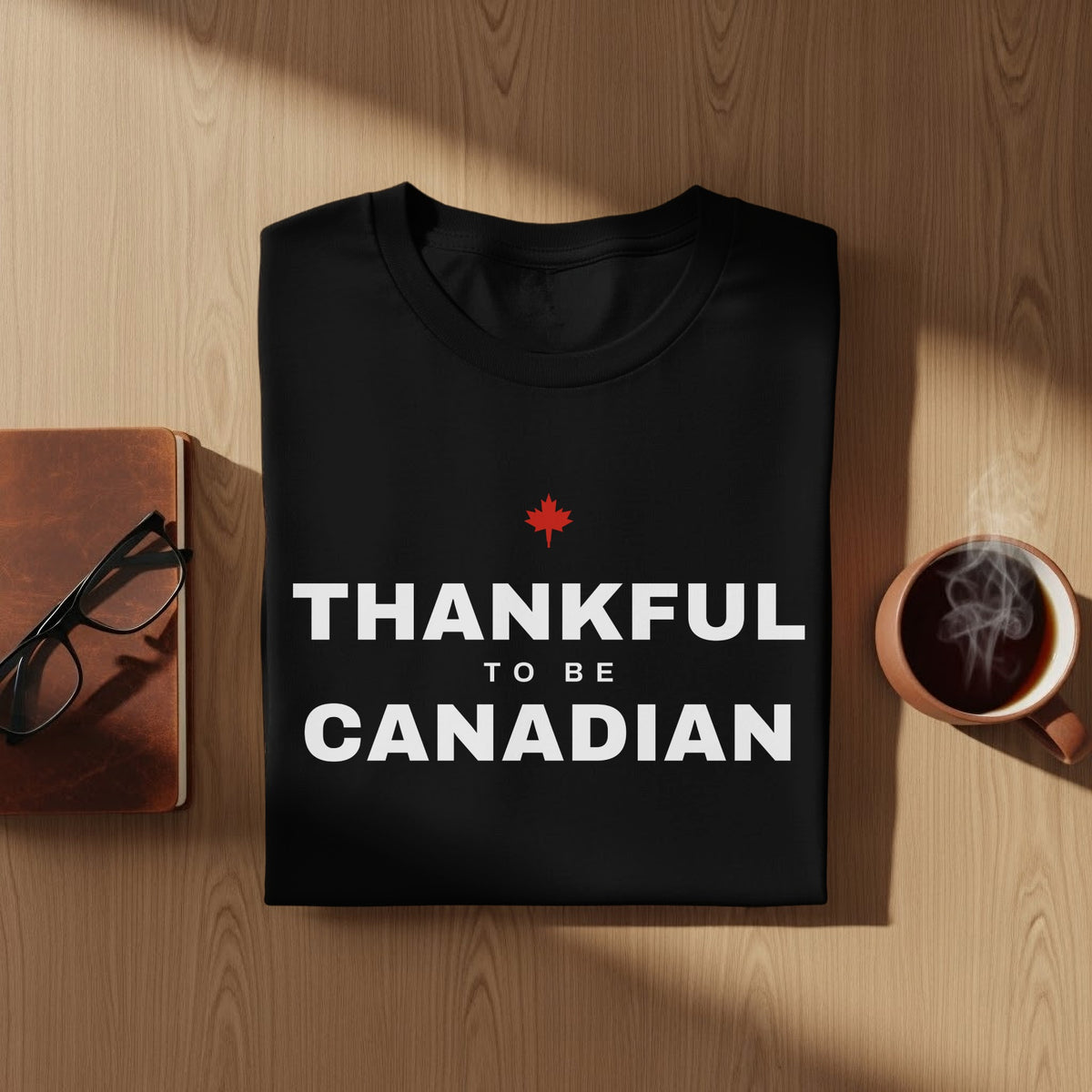 Black t-shirt with white text "THANKFUL TO BE CANADIAN" and a red maple leaf.