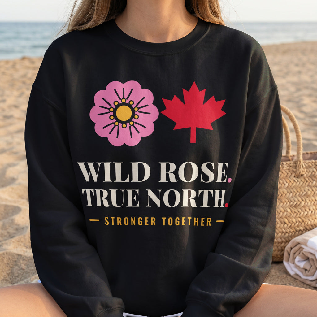 Black sweatshirt with pink wild rose, red maple leaf, and text "WILD ROSE. TRUE NORTH. STRONGER TOGETHER."
