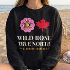 Black sweatshirt with pink wild rose, red maple leaf, and text "WILD ROSE. TRUE NORTH. STRONGER TOGETHER."