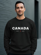 Man wearing black sweatshirt with "CANADA EST. 1867" and a maple leaf.