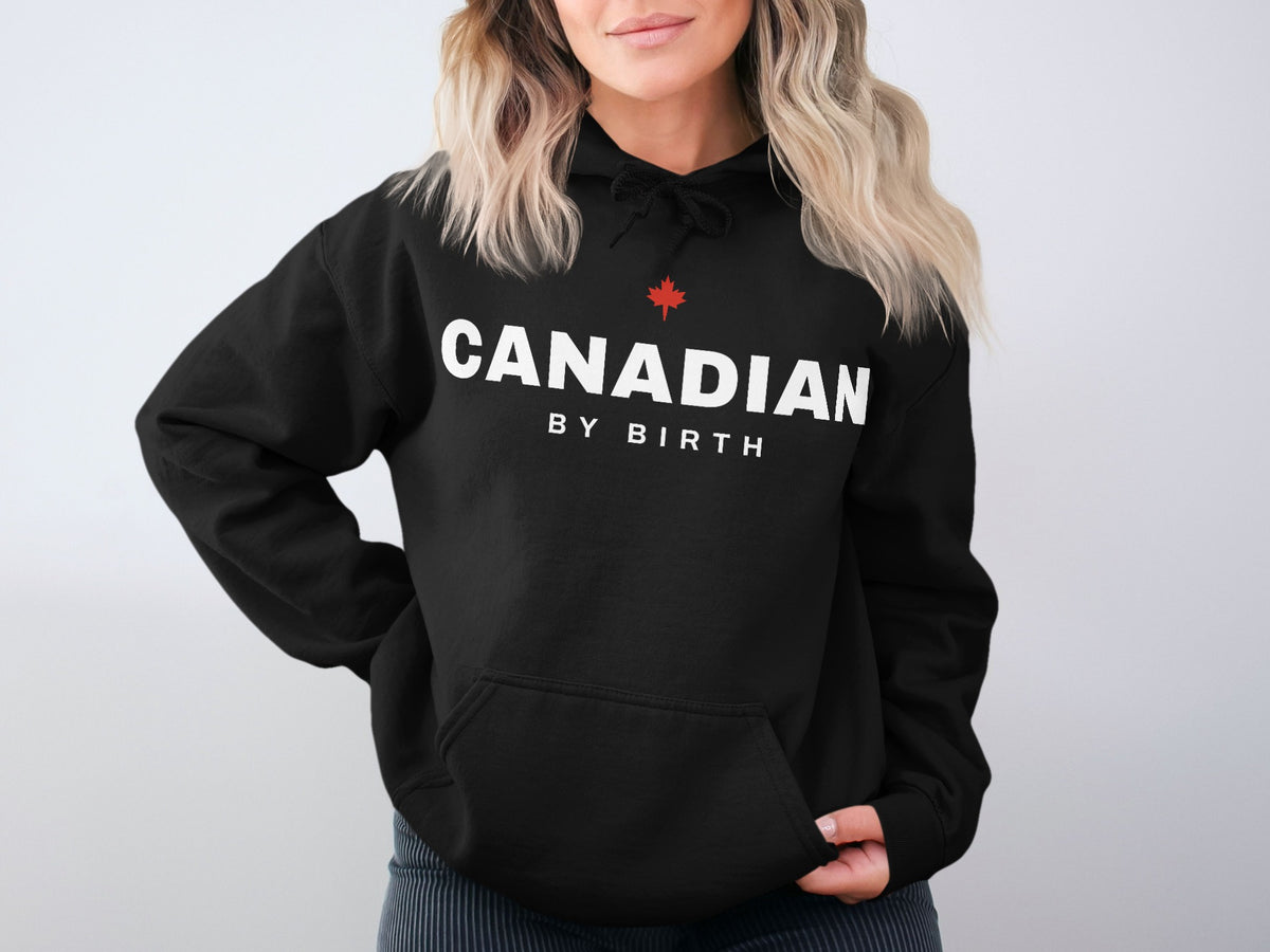 Black hoodie with white text "CANADIAN BY BIRTH" and a red maple leaf.