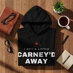 Black hoodie with "I GOT A LITTLE CARNEY'D AWAY" text and Canadian maple leaf graphic.