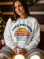 White sweatshirt with "Lake Ontario" text, sunset graphic, and "Great Lakes Canada" text.
