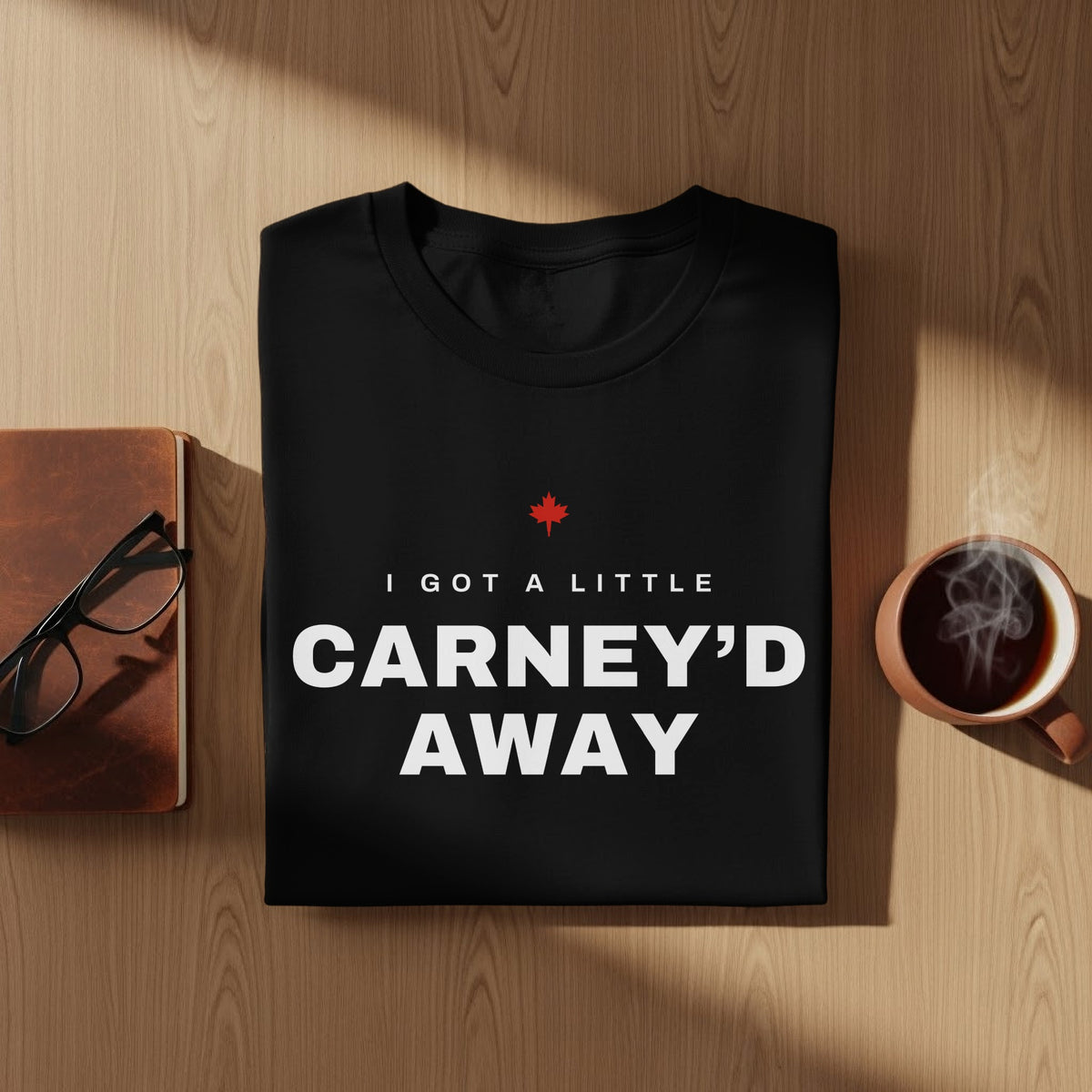 Black t-shirt with white text "I GOT A LITTLE CARNEY'D AWAY" and a red maple leaf.