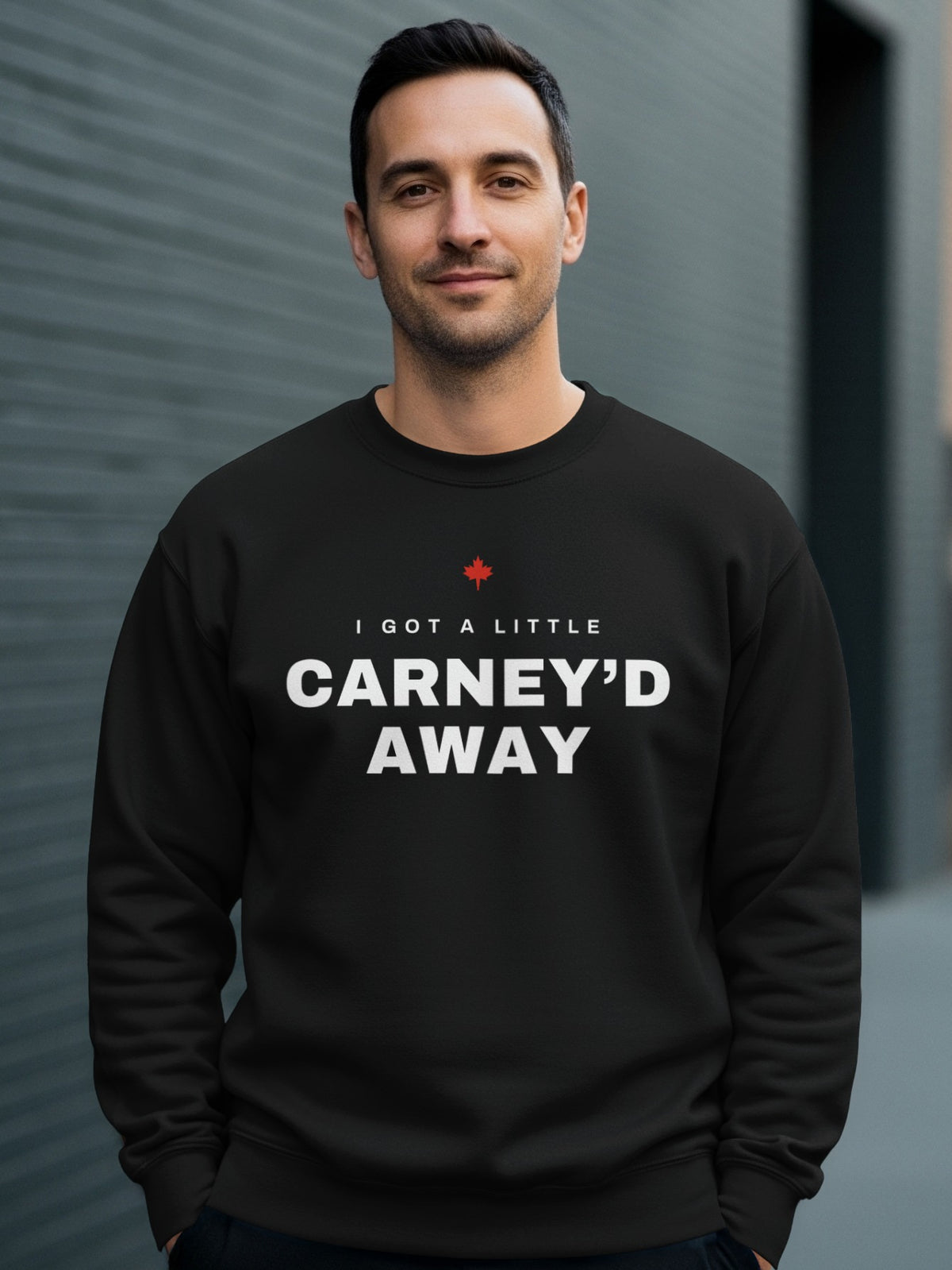 Black sweatshirt with white text "I GOT A LITTLE CARNEY'D AWAY" and a red maple leaf.