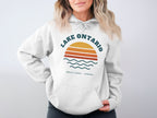 White hoodie with "Lake Ontario Great Lakes Canada" graphic and sunset design.