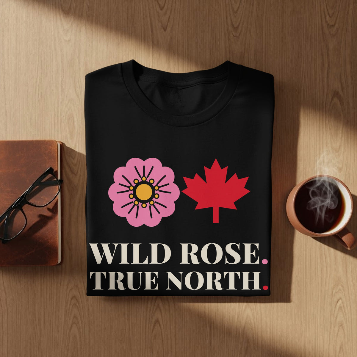 Black t-shirt with pink wild rose, red maple leaf, and text "WILD ROSE. TRUE NORTH."