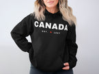 Black hoodie with "CANADA EST. 1867" and a maple leaf logo.